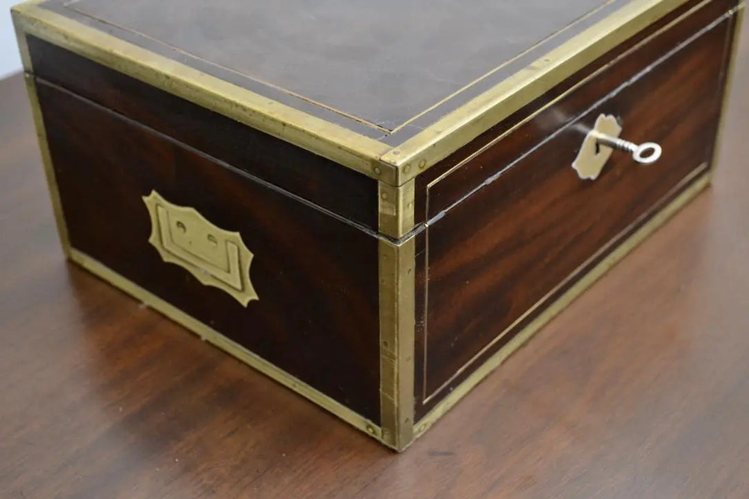 Corner view of Lady Liston brass writing box with side handle and key inserted.