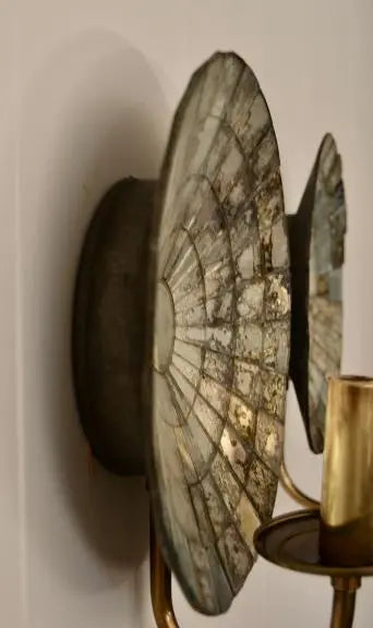 Side view of a vintage mirrored glass wall sconce showing the layered reflective disc design and brass holder.