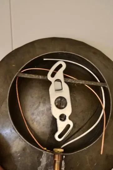 Backside wiring and mounting bracket of an antique mirrored wall sconce, showing metal and copper components.