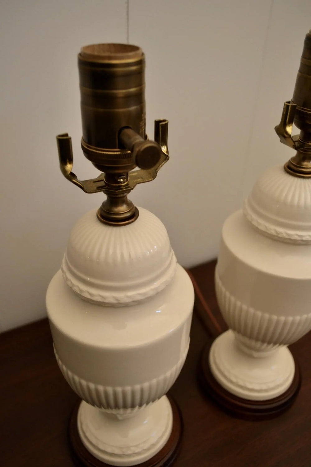 Close-up view of vintage cream ceramic lamps showcasing brass fittings and textured detailing.