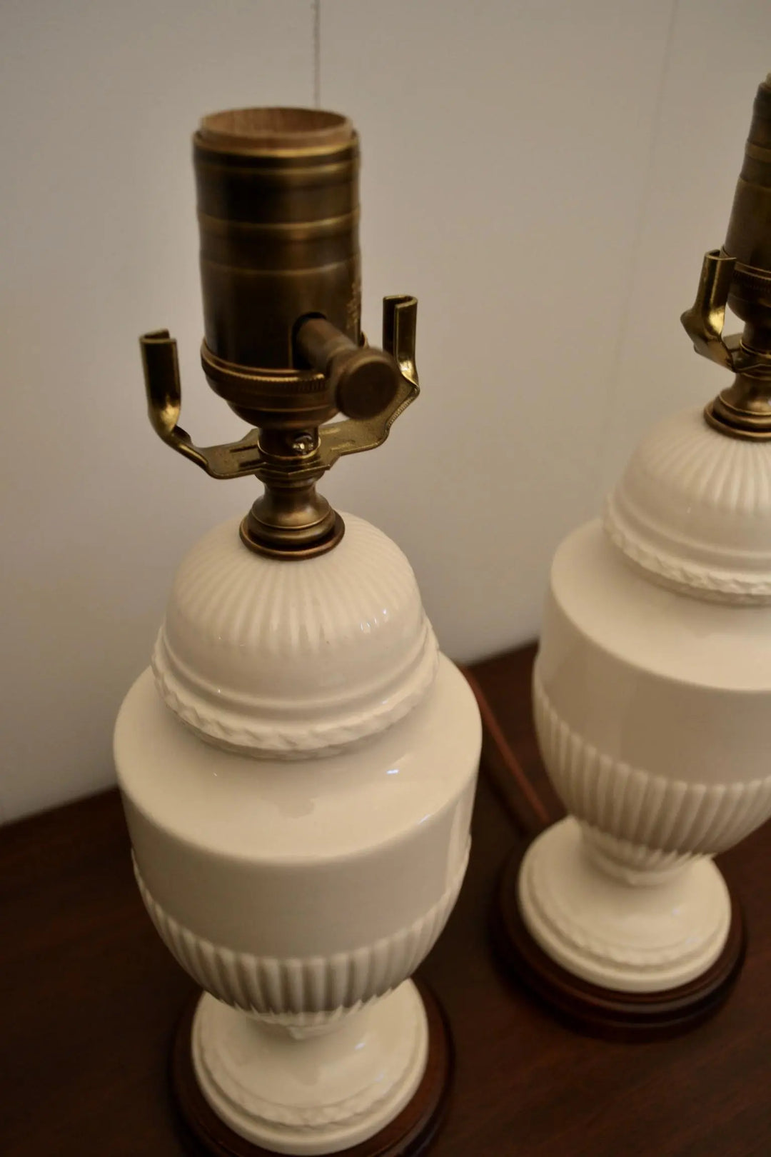 Close-up view of vintage cream ceramic lamps showcasing brass fittings and textured detailing.