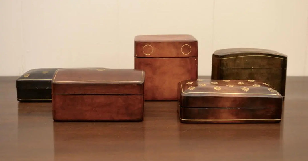Collection of five Japanese lacquered decorative boxes with gold inlay patterns, displayed on a wooden surface.