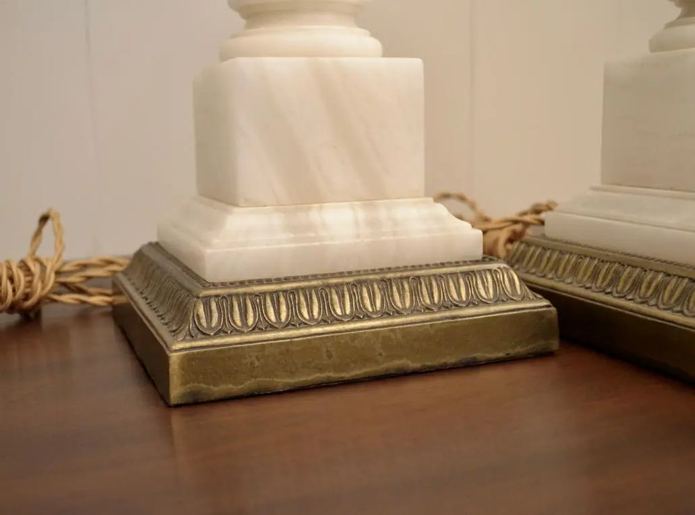 Close-up of the square white marble base and ornate brass trim of a vintage neoclassical table lamp.