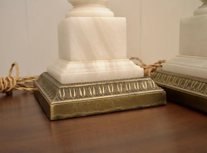 Close-up of the square white marble base and ornate brass trim of a vintage neoclassical table lamp.