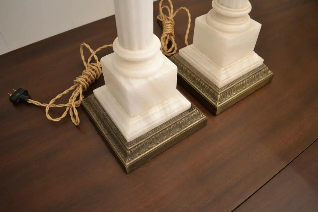 Overhead view of vintage white marble column lamps with decorative brass bases on a wood surface.
