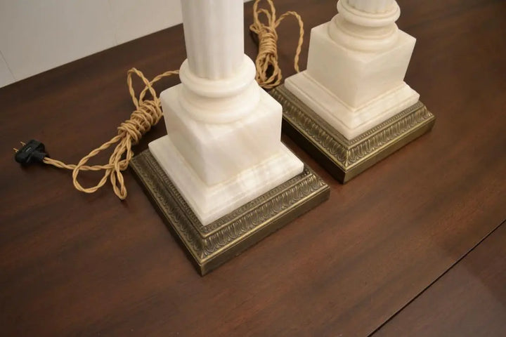 Overhead view of vintage white marble column lamps with decorative brass bases on a wood surface.
