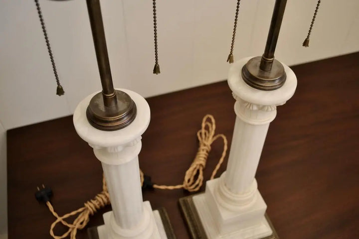 Top view of white marble column table lamps showing brass sockets and pull chains.