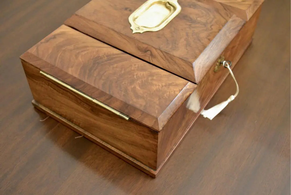 Side angle of antique walnut tea caddy with brass accents and decorative key tassel