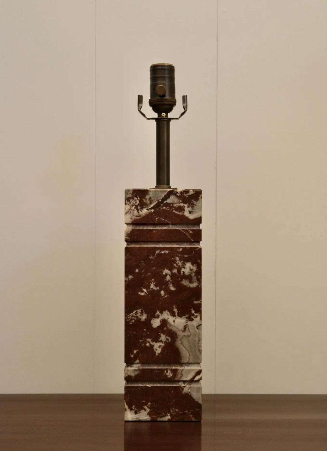 Front view of tall red marble table lamp with geometric silhouette and bronze socket