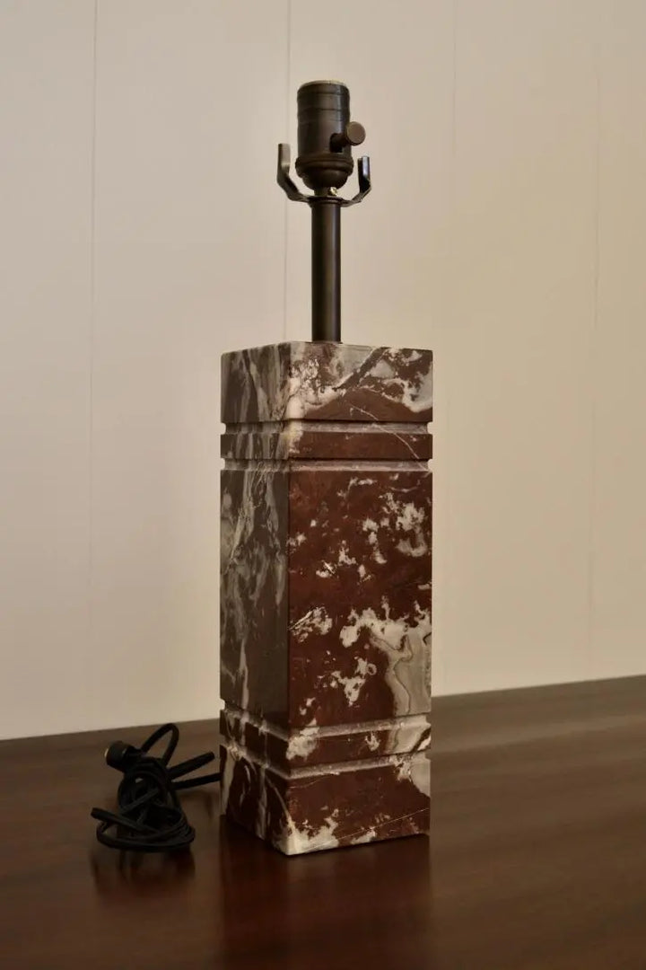Side angle view of square red marble lamp with dark bronze socket and marbled texture