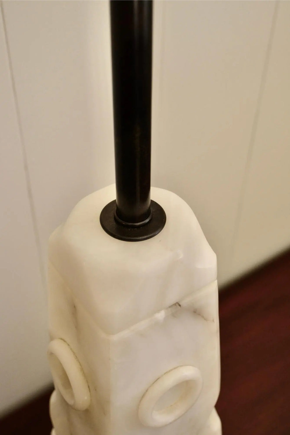 Close-up of metal rod inserted into sculpted white alabaster lamp.