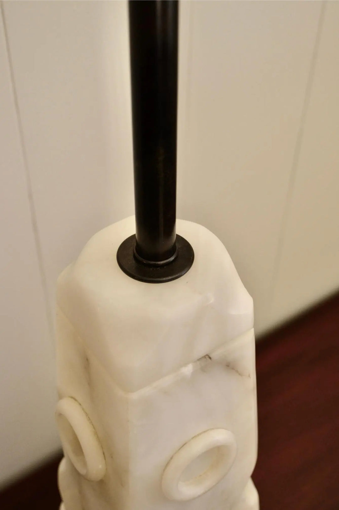 Close-up of metal rod inserted into sculpted white alabaster lamp.