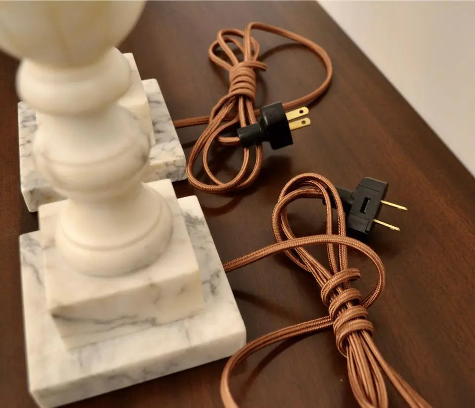 Close-up of electrical plugs and cords of vintage marble table lamps on dark wood surface