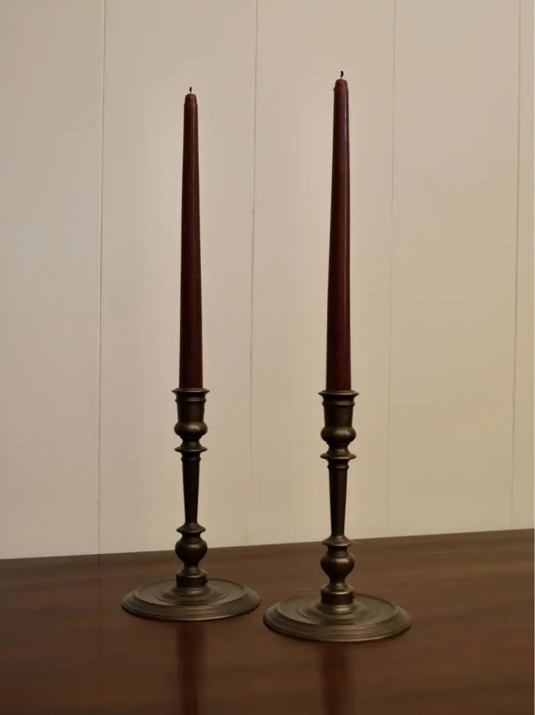 Pair of vintage bronze candlestick holders with tall burgundy taper candles