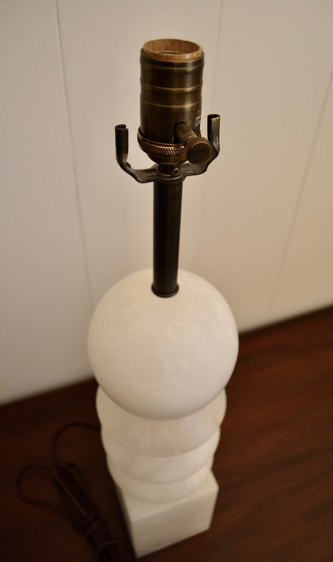 Top-down view of alabaster table lamp with sphere and diamond-cut layers, highlighting brass light socket and dark metal neck.