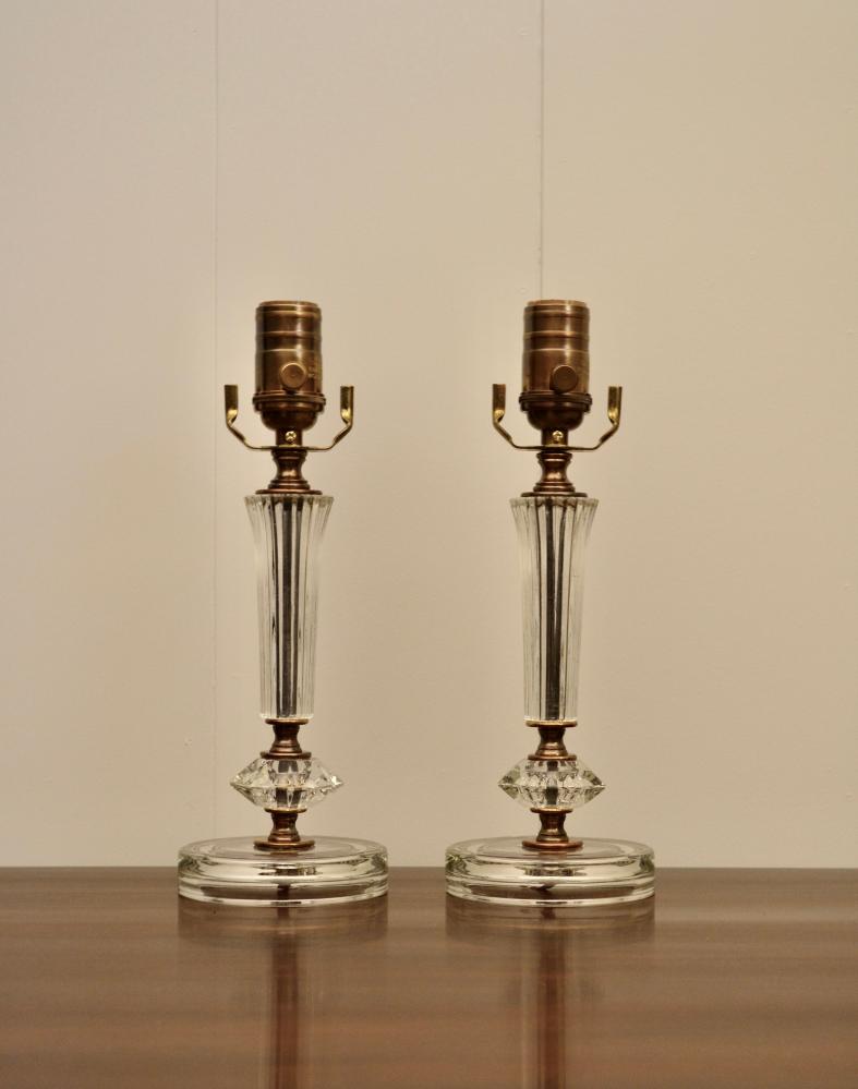 Pair of antique glass lamps with ribbed stems and round bases placed on wooden surface