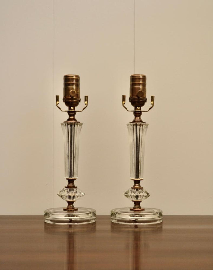 Pair of antique glass lamps with ribbed stems and round bases placed on wooden surface