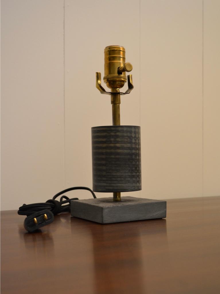 Small black and brass table lamp with square slate base and cylindrical textured body