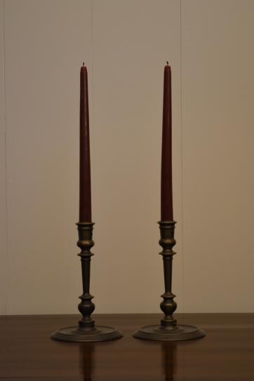 two vintage bronze candlestick holders with burgundy taper candles