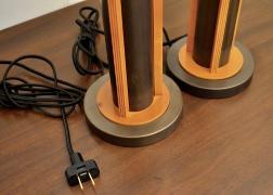Close-up of the base and power cords of modern industrial table lamps with dark bronze metal and reddish wood detailing.