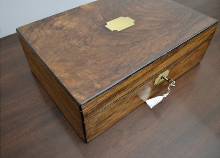 Angled view of antique mahogany jewelry box with brass key and top inlay accent