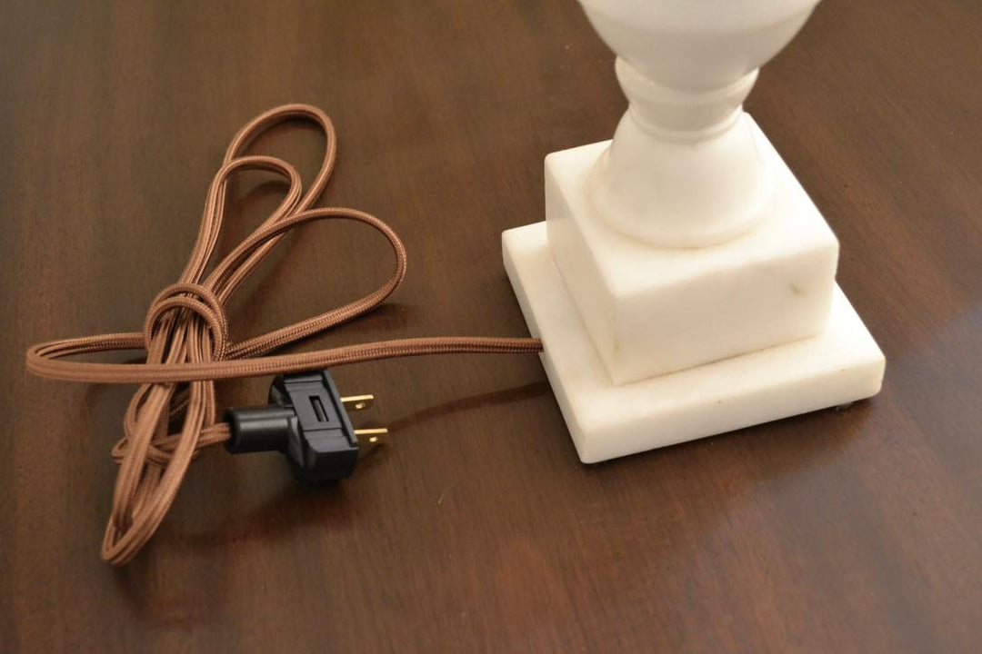 Brown fabric-wrapped electrical cord and plug attached to square marble lamp base