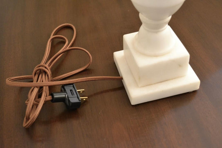 Brown fabric-wrapped electrical cord and plug attached to square marble lamp base