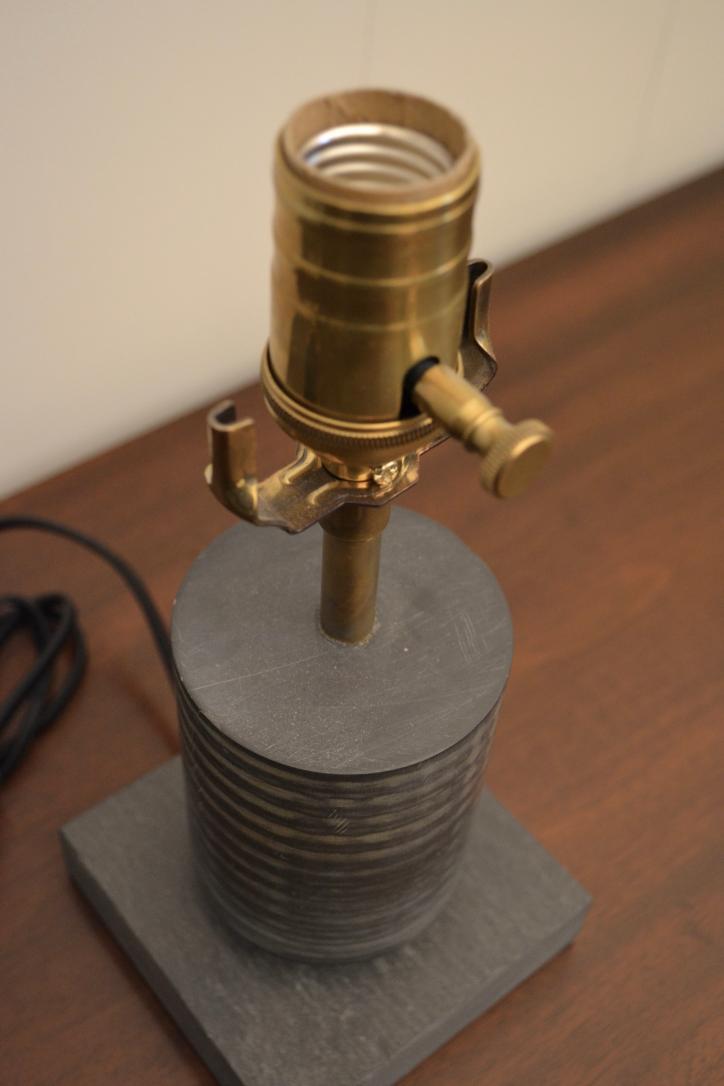 Angled top-down view of modern black and brass table lamp showing lamp socket and cylindrical base