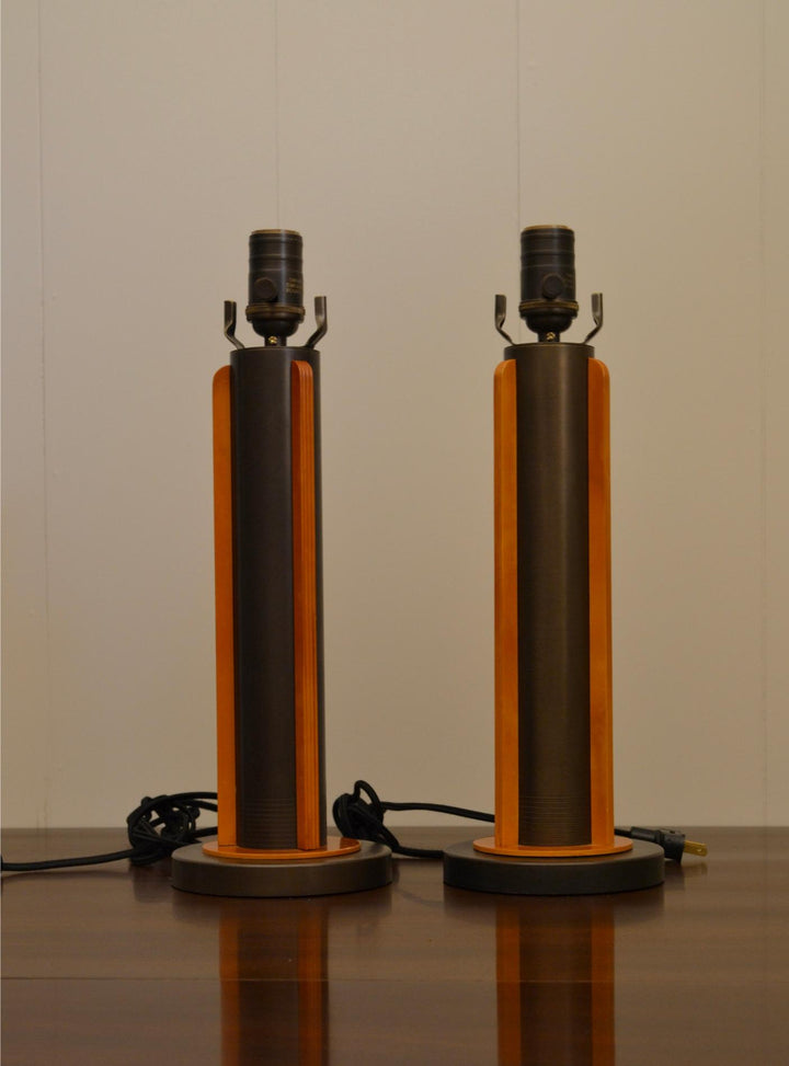 Straight-on view of a pair of modern industrial table lamps with cylindrical metal frames and symmetrical wood accents.
