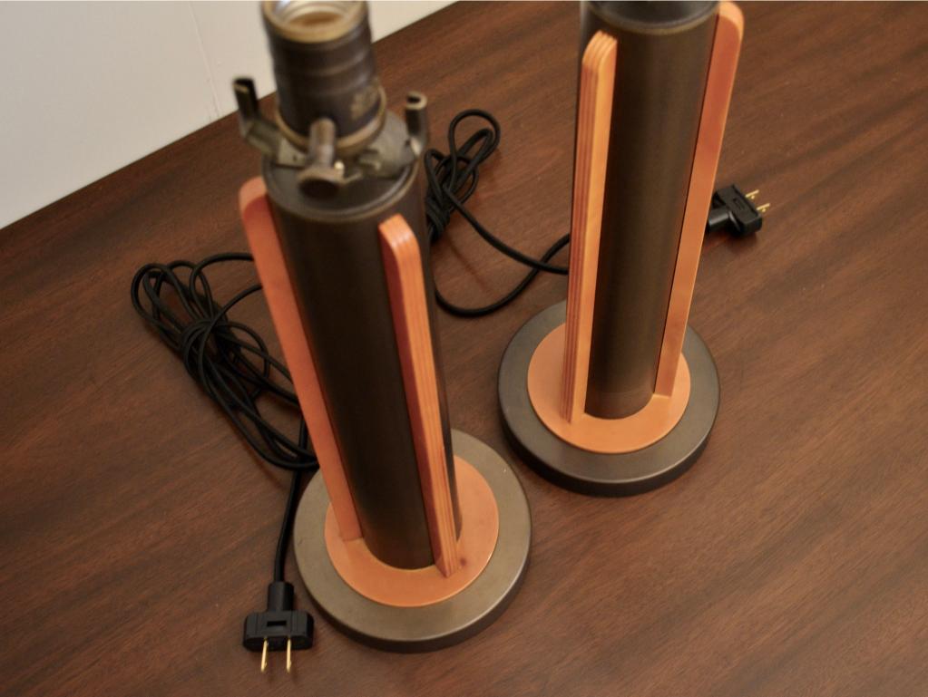 Top-down view of modern table lamps showing cylindrical metal bodies with vertical wooden panels and black cords.