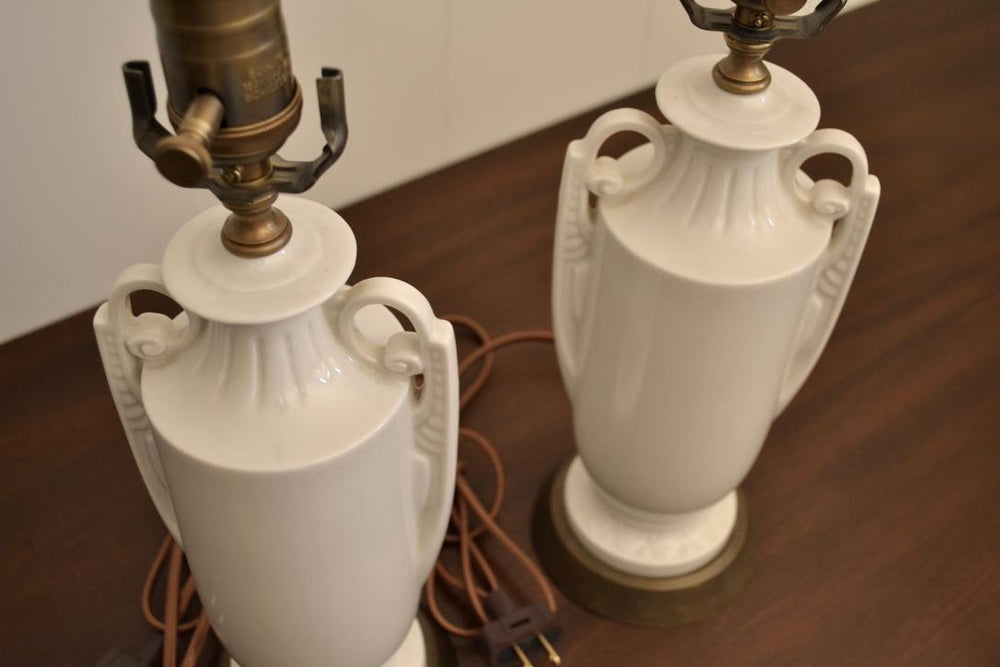 Pair of vintage white ceramic urn lamps with sculpted handles and brass hardware