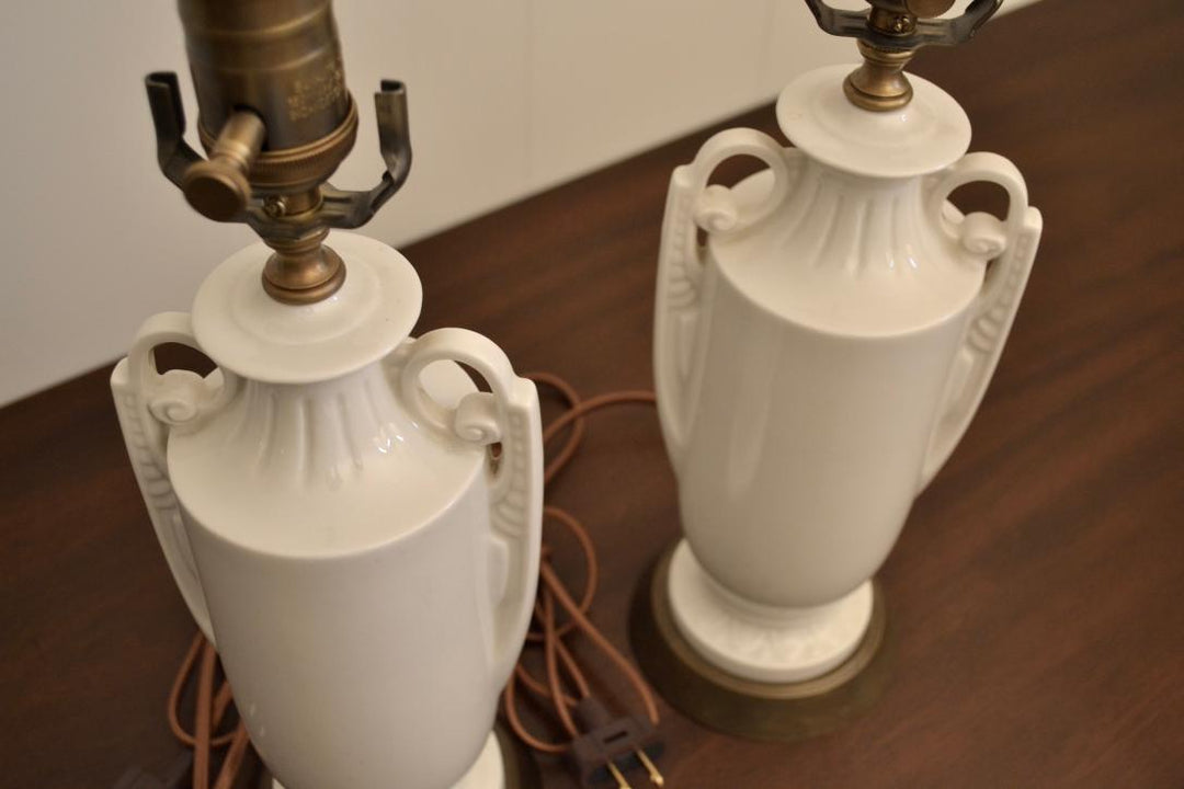 Pair of vintage white ceramic urn lamps with sculpted handles and brass hardware