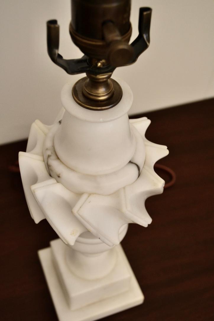 Close-up of vintage white marble lamp with brass socket and sculpted swirl design
